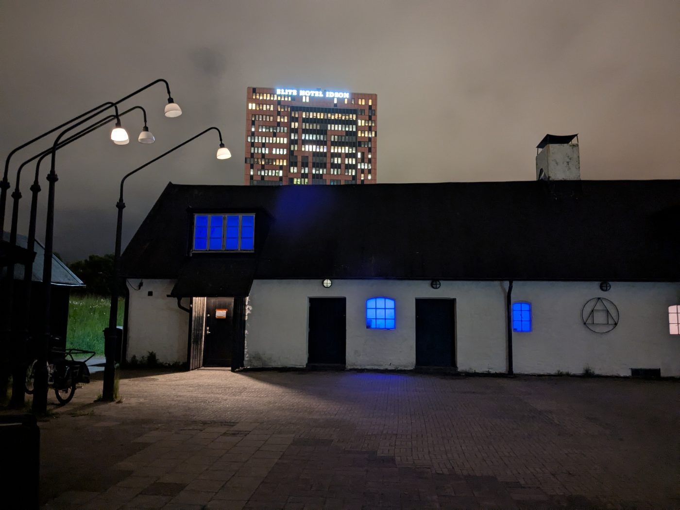 Lophtet en kväll, den vitkalkade längan med blåbelysta fönster och Hotel Ideon bakom